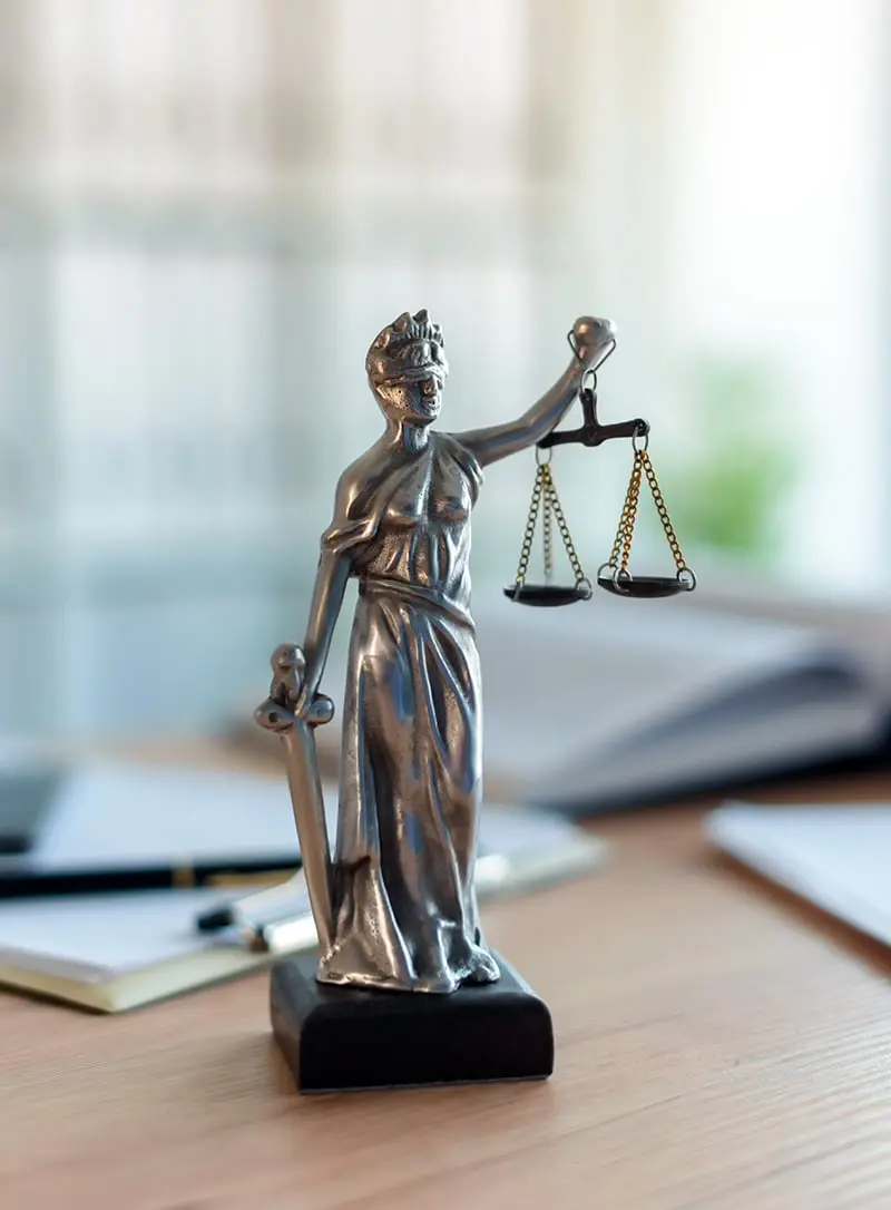 Estatua de la justicia con libros y agenda sobre una mesa