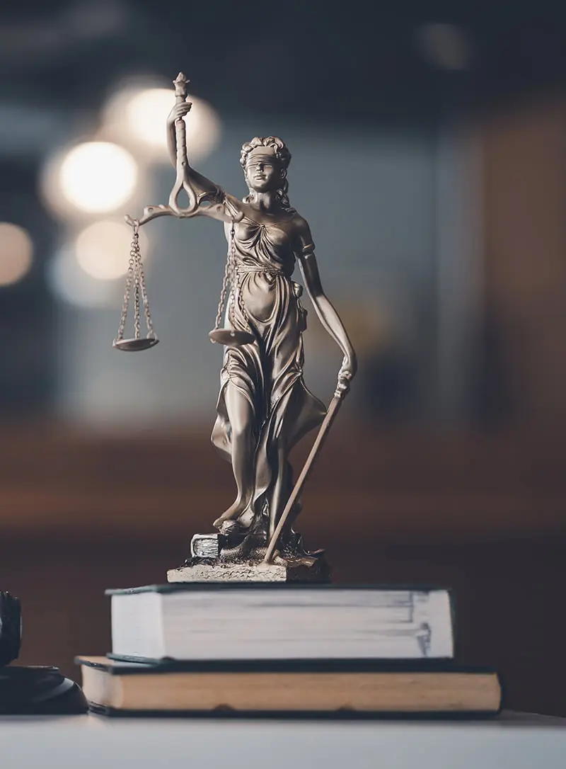 Estatua de la justicia sobre dos libros en una mesa
