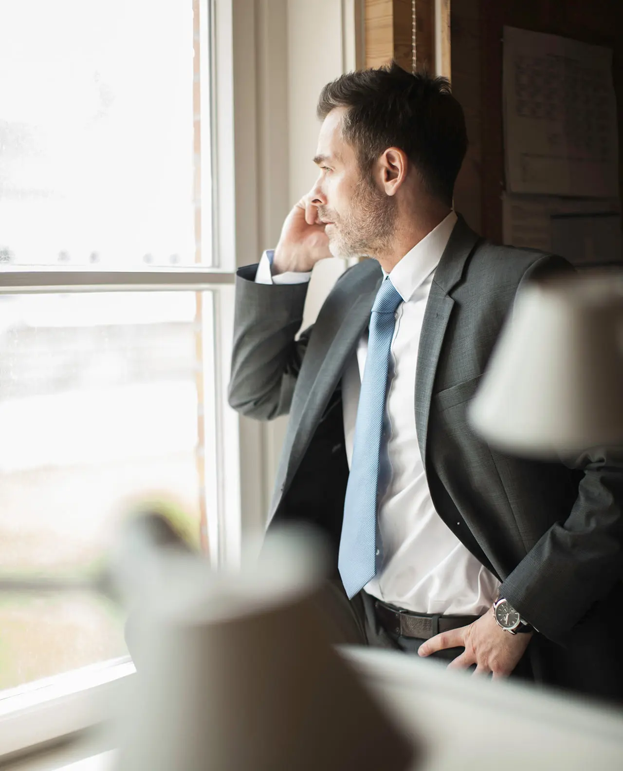 Hombre de negocios hablando por telefono mientras mira por la ventana