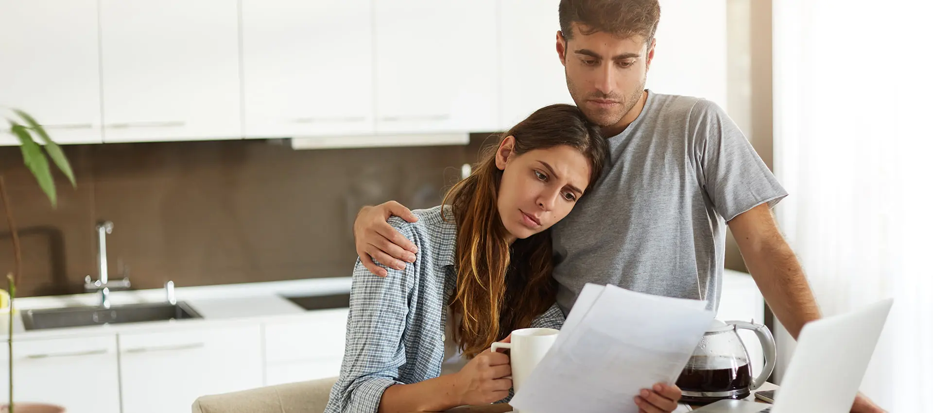 Pareja de jovenes mirando facturas en una cocina
