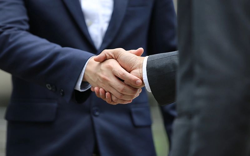 Dos hombres dándose la mano después de llegar a un acuerdo por una reclamación de gastos y comisiones bancarias sobre la hipoteca